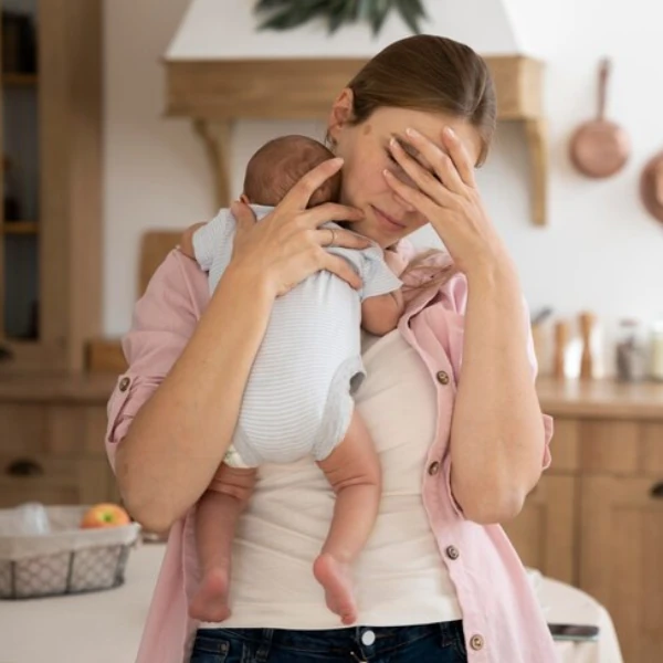 Madre preocupada con su bebé en brazos tras ser golpeada, representa la dificultad de lidiar con un bebé que pega, en el contexto de la crianza respetuosa.